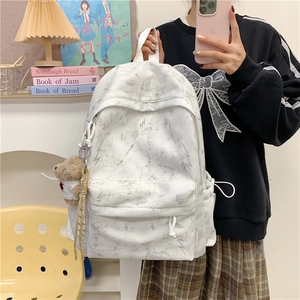 Detail of white marble pattern backpack with side pocket and brown plush bear charm