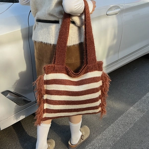 Detail view of large knit tote bag with brown white stripes and fringe tassel edges