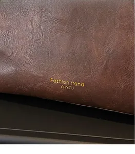 Close-up of deep brown lychee grain leather with gold Fashion Trend logo engraving