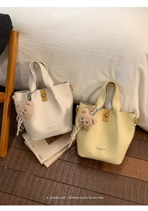 Close-up of pebble leather bucket bags with gold twist locks and plush bear charms