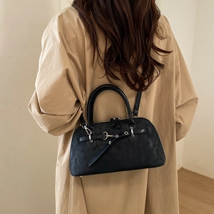 Detail view of a vintage black Boston shoulder bag worn with a stylish trench coat