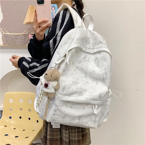 Detail view of large white marble pattern backpack with a cute teddy bear plush charm