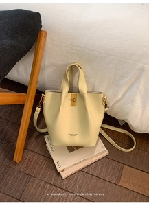 Detail of cream white lychee leather bucket bag with gold clasp on magazine