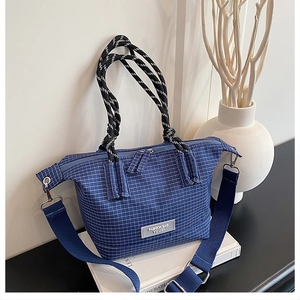Close-up of blue plaid handbag with woven rope handles and adjustable shoulder strap