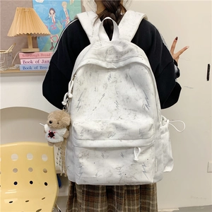 Close-up of white marble pattern backpack with embroidery and a cute bear charm