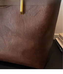 Close-up of deep brown pebbled leather texture with gold cylindrical metal accents