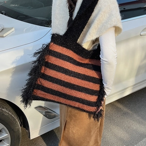 Close-up of black and red striped knit tote bag with long side fringe details