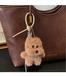 Close-up of plush puppy bag charm with silicone strap on a brown leather tote bag