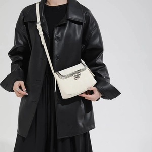 Detail der minimalistischen beigen Umhängetasche mit Vintage-Metallkugelverschluss und Mattleder