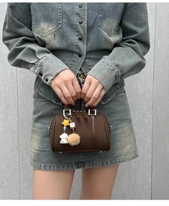 Detail of dark brown Boston bag with pebbled texture and cute decorative charms