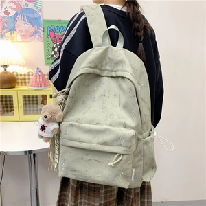 Detail of light green canvas backpack with marble texture and plush bear charm