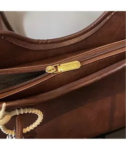 Detail of dark brown leather handbag with glossy gold zipper and vintage texture