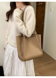 Detail of beige leather tote bag featuring elegant knotted handles and pebble texture