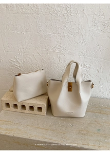 Detail of cream white litchi pattern leather bucket bag set with metal twist lock