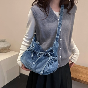 Detailed view of dark blue denim shoulder bag with bow drawstrings on a model