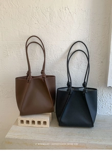 Detail of dark brown and black minimalist tote bags with pebble grain texture and knotted straps
