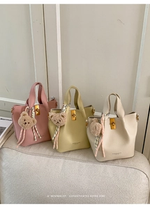 Detailed view of fashionable bucket bags in pink, green, and beige with plush bear charms
