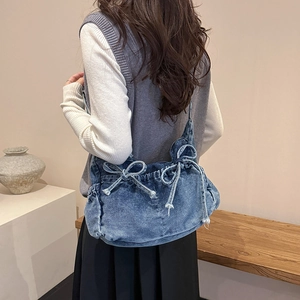 Blue denim bow shoulder bag styled with casual outfit in a minimalist indoor setting