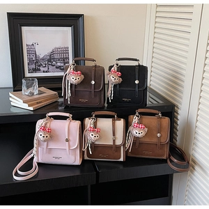 Detail view of five retro color backpacks with cute bear charms on a wooden surface