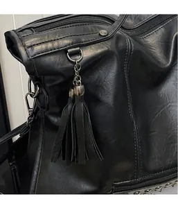 Close-up of black leather tote bag featuring a double-layer tassel and metal studs
