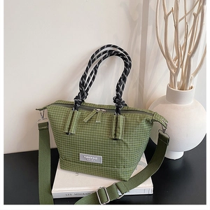 Detail of army green plaid canvas tote bag showing fashion tag and woven handle