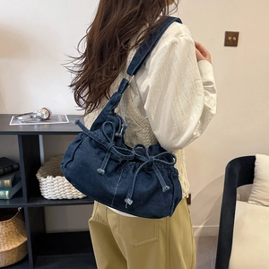 Detailed view of the dark denim texture and bow accents on this stylish hobo shoulder bag