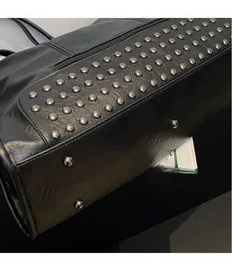 Detail of silver rivets on matte black leather tote with protective metal bottom studs