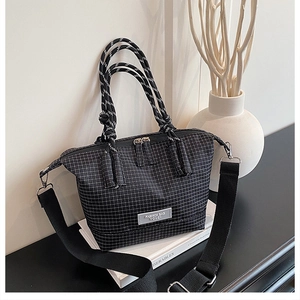 Detail of black plaid tote bag with woven rope handles and adjustable nylon shoulder strap