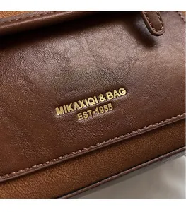 Close-up of caramel leather bag showing the vintage litchi texture and gold logo imprint