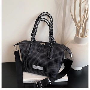 Detail of black and white plaid handbag with knot handles and adjustable shoulder strap