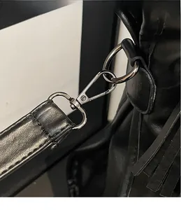 Close-up of durable silver metal lobster hook and reinforced stitching on a black tote bag