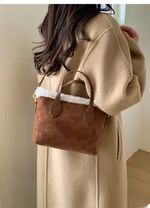Close-up of brown suede bucket bag with white faux fur trim and embossed monogram texture