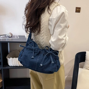 Close-up of dark blue denim hobo bag with bow details and elegant gathered pleats