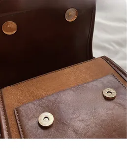 Detail of vintage leather backpack showing high-quality gold magnetic snap closures