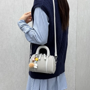 Light grey Boston bag with woven texture, cute bear charm, and adjustable shoulder strap