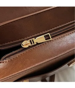 Close-up of golden metal zipper pull and textured brown leather on vintage backpack