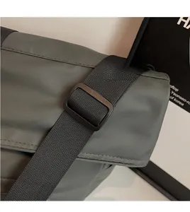 Détail de la bandoulière réglable en nylon avec boucle noire mate sur un sac fourre-tout
