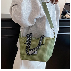 Close-up of green checkered crossbody bag featuring woven handles and wide shoulder strap