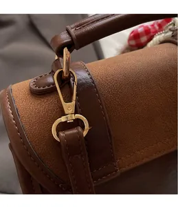 Detail of high-gloss gold metal hook on brown leather and suede patchwork bag