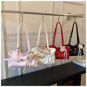 Detail showing high-gloss patent leather handbags in four colors with plush bear charms