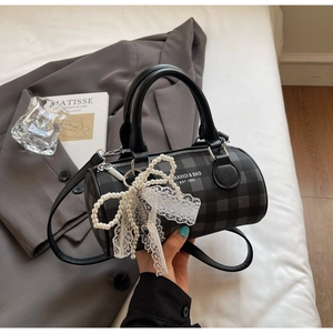 Détail du sac cylindrique à carreaux noir et gris avec nœud en dentelle et perles