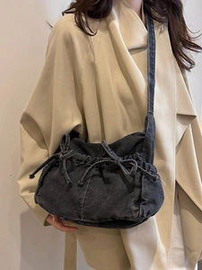Denim bow hobo bag in black washed finish shown on a model with a beige coat