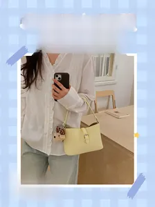 Minimalist light yellow shoulder bag detail with a cute teddy bear charm and metal buckle