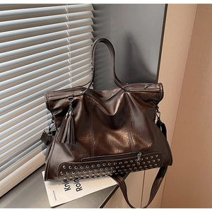 Detailed view of dark brown vintage leather tote bag with silver studs and tassel detail