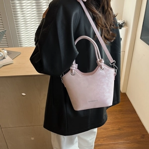 Detail view of the pink bucket bag with knot handles and adjustable shoulder strap