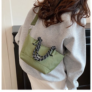 Close-up of green plaid canvas bag with thick rope handle and silver metal hardware details