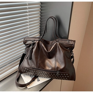 Detail of vintage brown patent leather tote bag with silver rivets and leather tassel