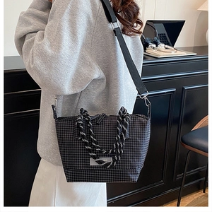 Detail of black and white checkered crossbody bag with unique woven rope top handle