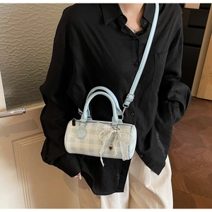 Détail d'un petit sac à main à carreaux bleus avec nœud en dentelle porté par un mannequin