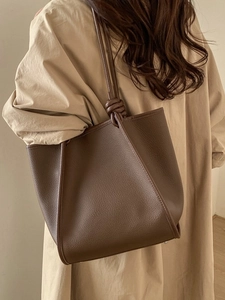 Vintage brown leather tote bag with knotted straps and pebble texture on female model